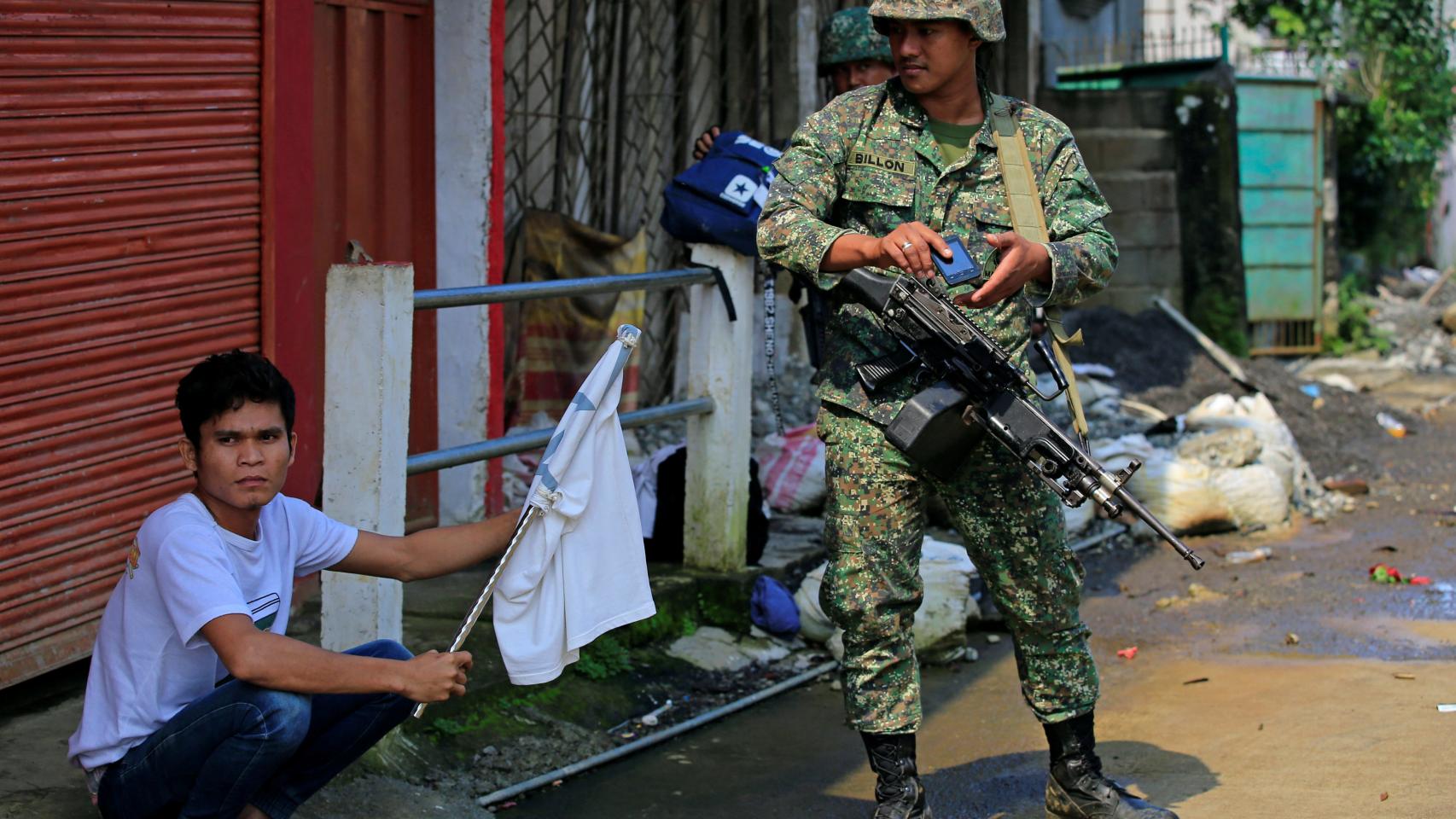 Un civil con una bandera blanca junto a un soldado filipino en Marawi