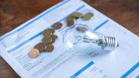 Una factura de la luz junto a varias monedas.