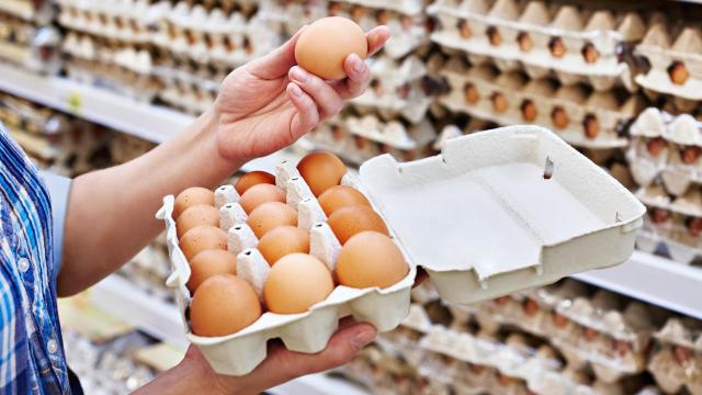 Una mujer sostiene una bandeja de huevos envasados.